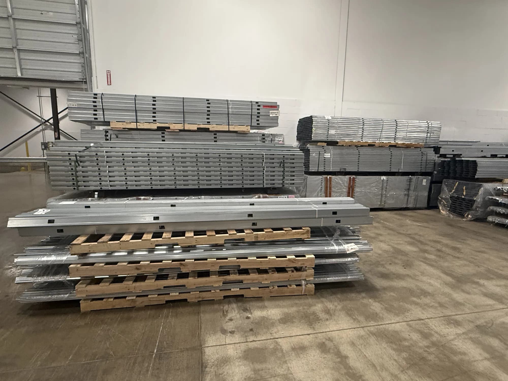 Wrapped bundles of steel framing staged beside the loading dock door